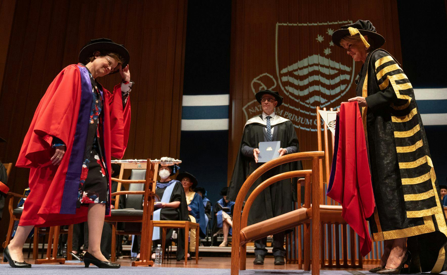Frances Adamson walks across the stage in her gown to collect an honorary degree from Julie Bishop.