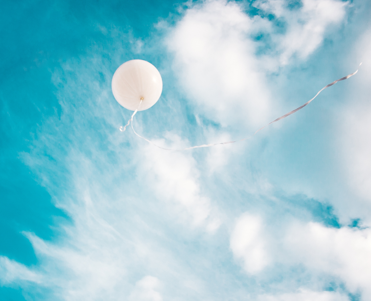 White balloon floating into the blue sky