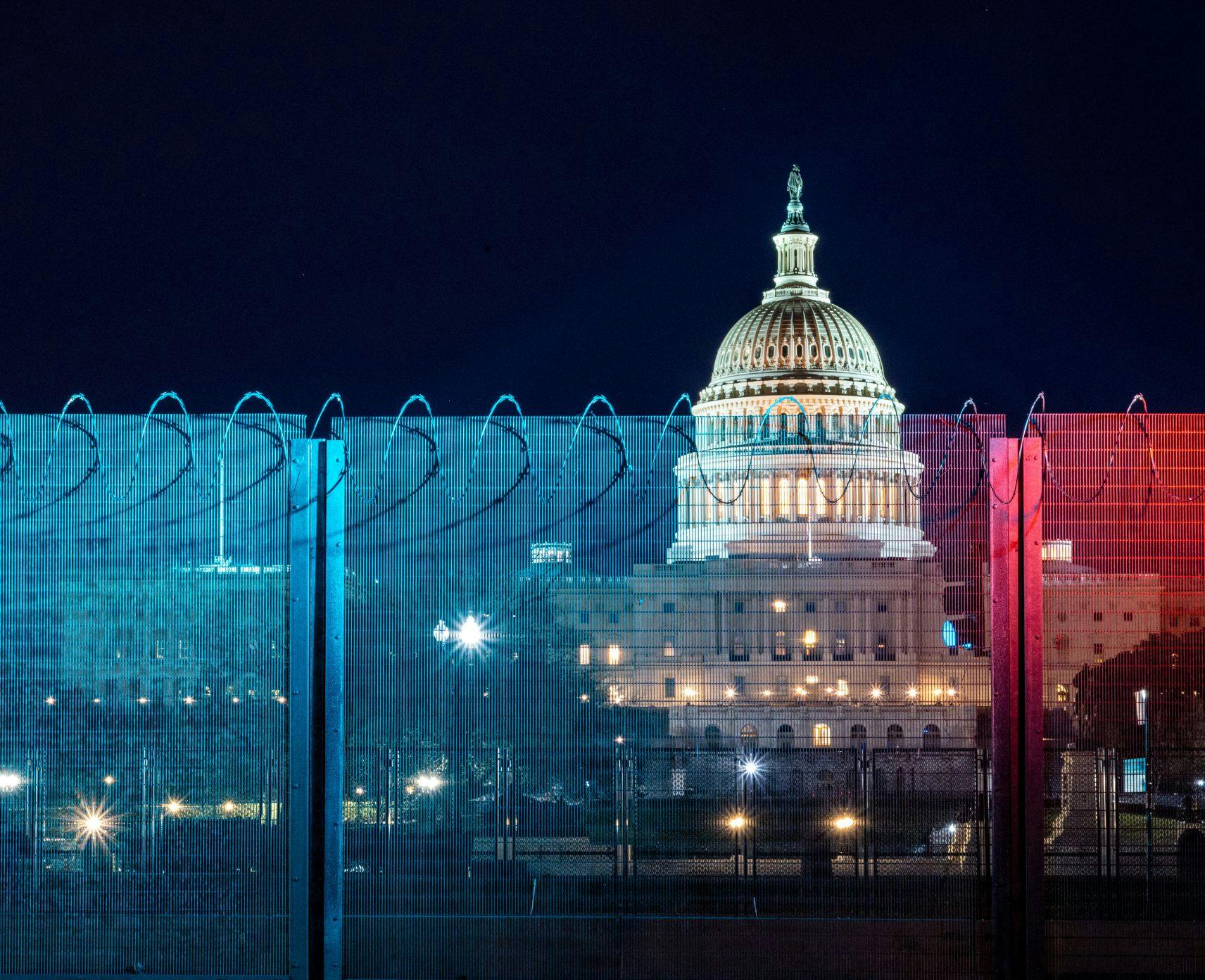 Security fence with blue and red light in front of the United States Capitol