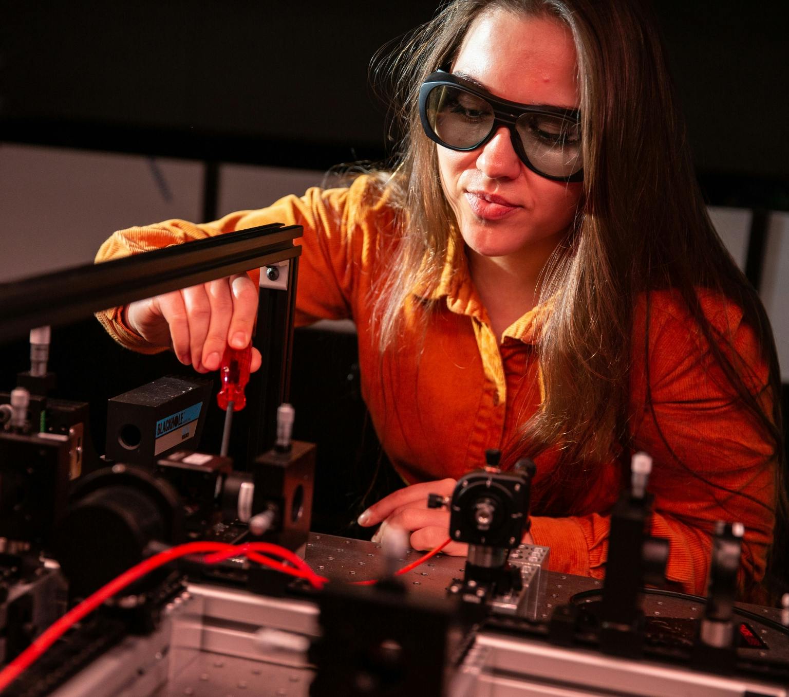 Anastasiia Zalogina working with equipment in the physics lab. She is wearing black goggles.