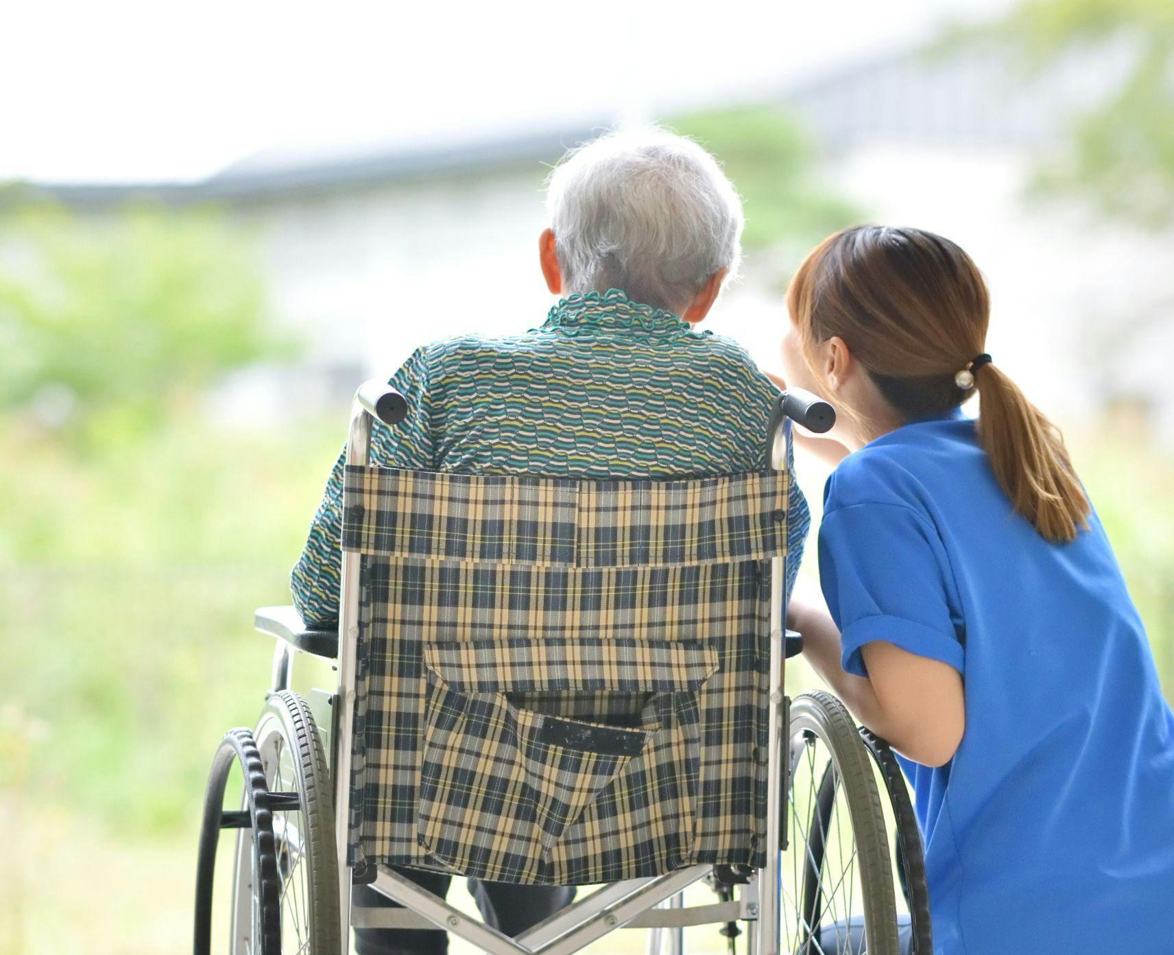 Older person in a wheelchair talking to a nurse