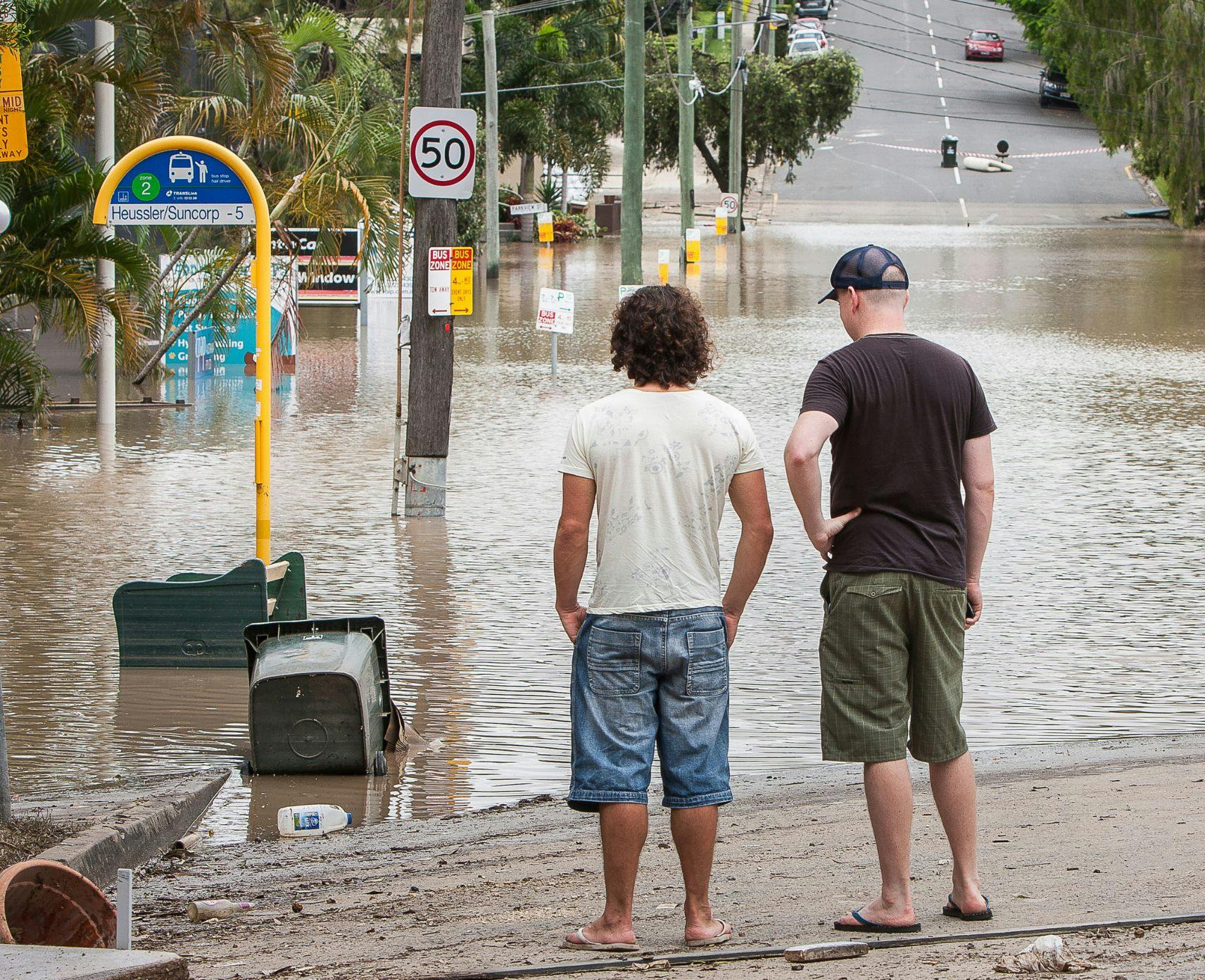 Two men stare at flood waters