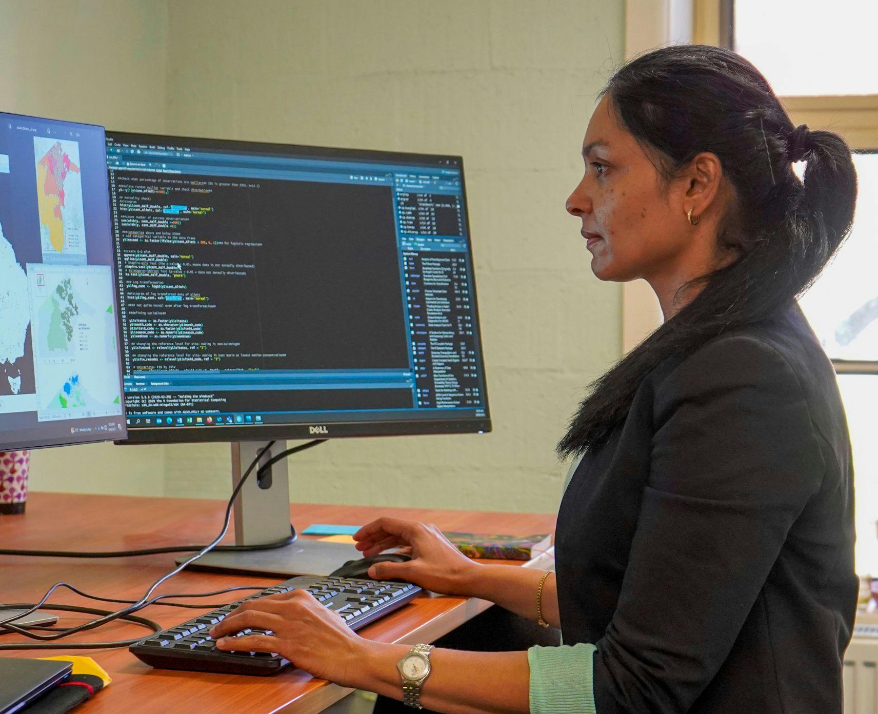 Associate Professor Aparna Lal at her desk, facing her computer.
