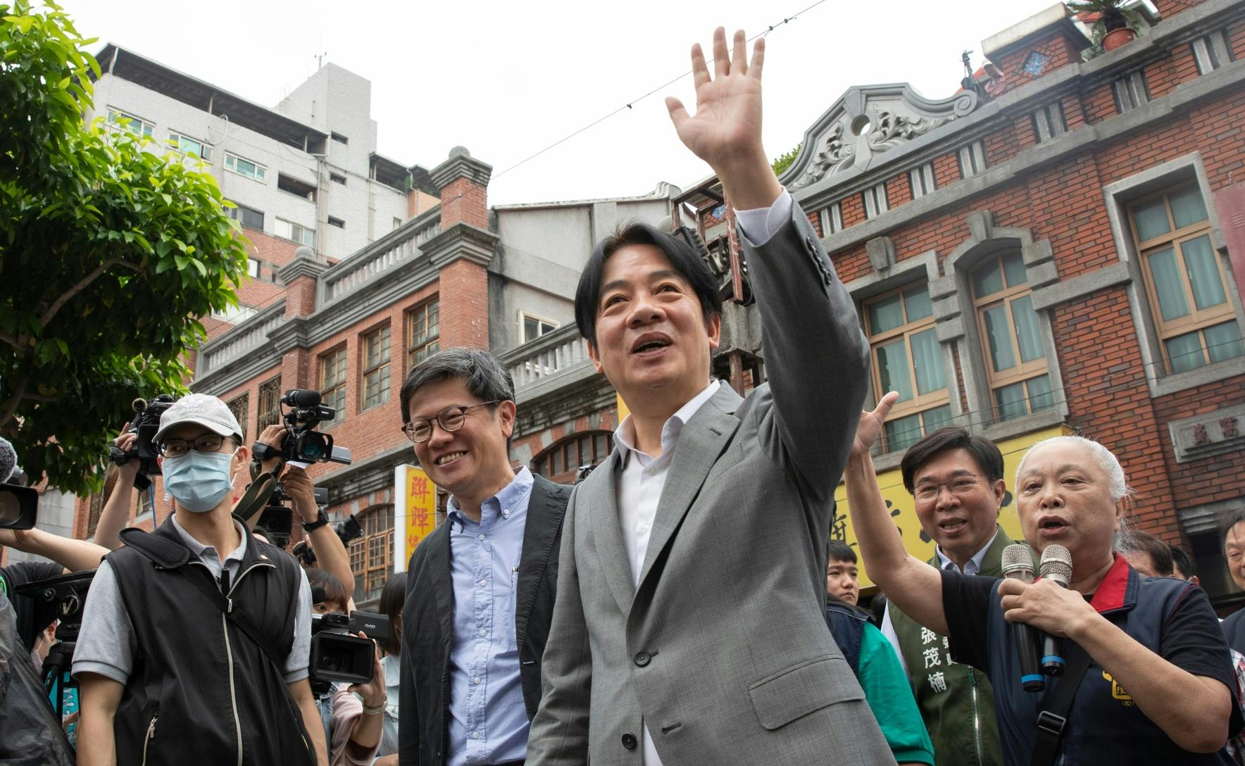 Lai Ching-te wears a grey suit and waves to ground while campaigning in Taipei for the Taiwan election, 25 March 2023