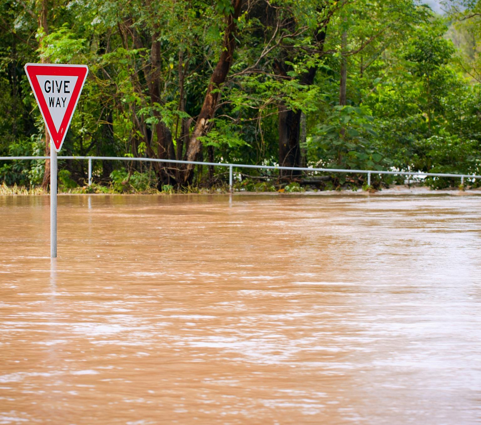 a flooded road in Queensland with a give way sign sticking out from the water