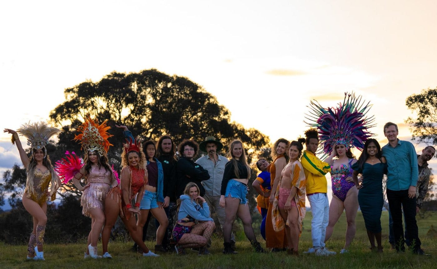 A combination of drag queens, ballet dancers and Brazilian funk dancers wearing colourful costumers filled to the brim with sequins. They are all dancing in a field in regional Victoria.