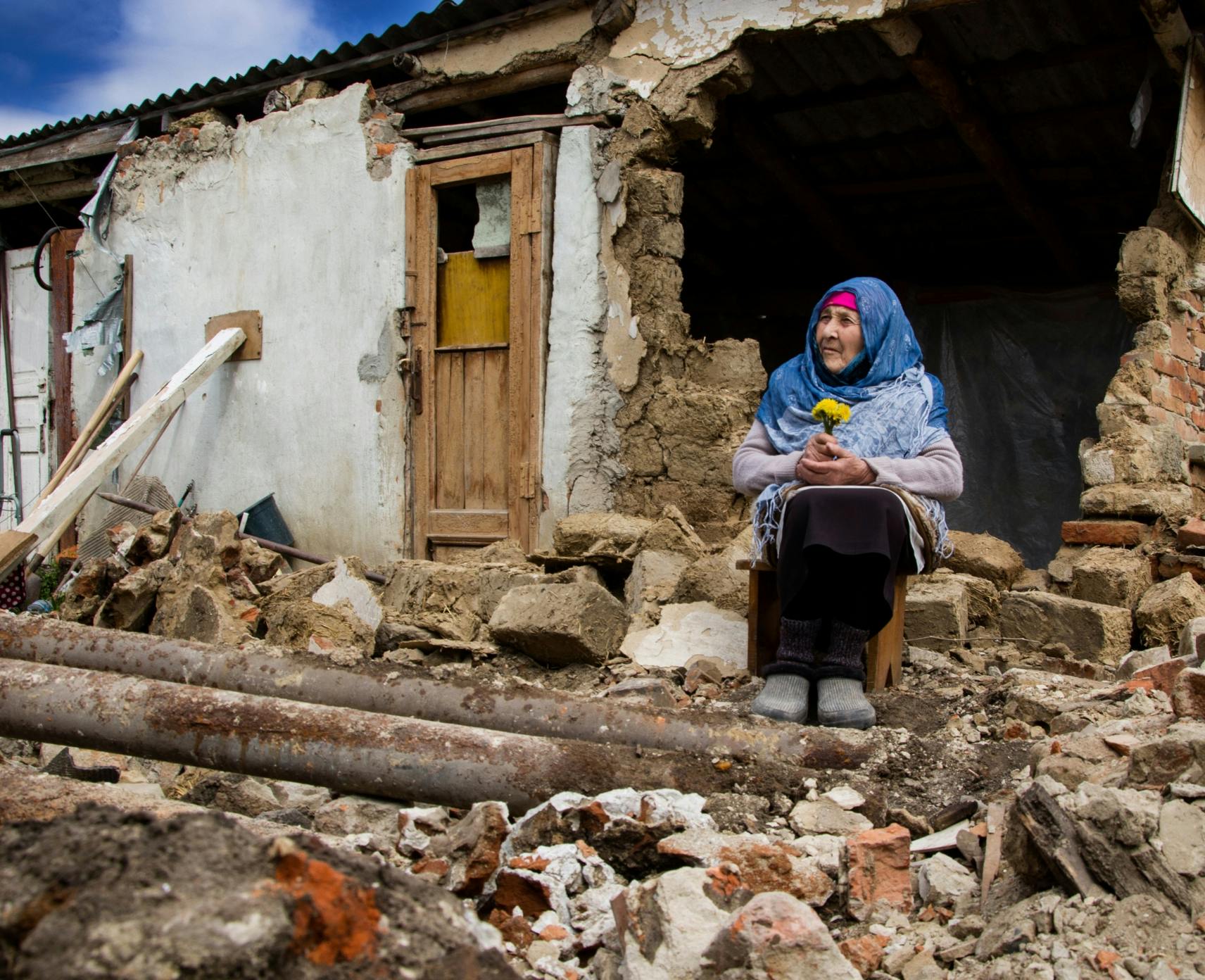 A woman prays in front of a war-torn house in Ukraine.