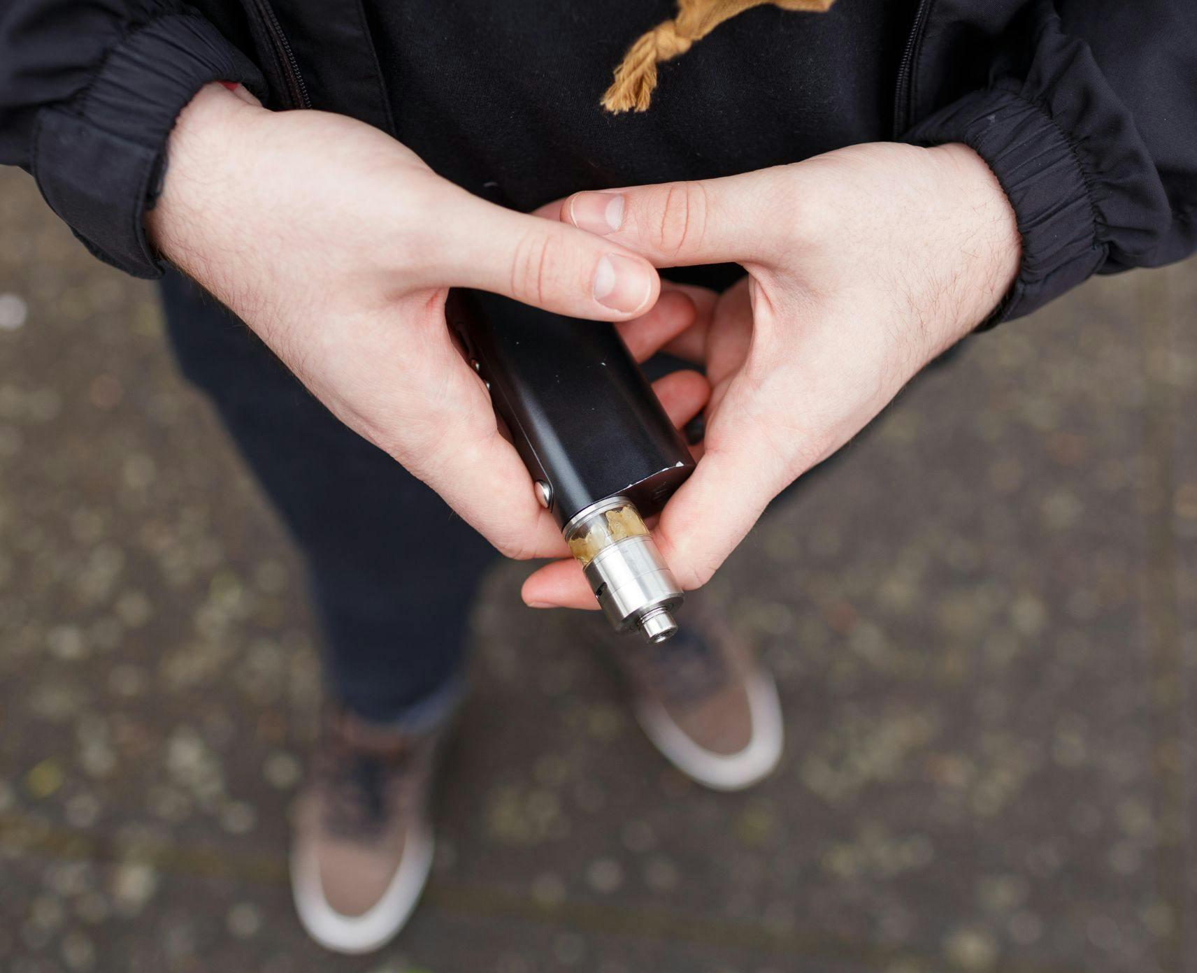 Person holding a vape in hands.