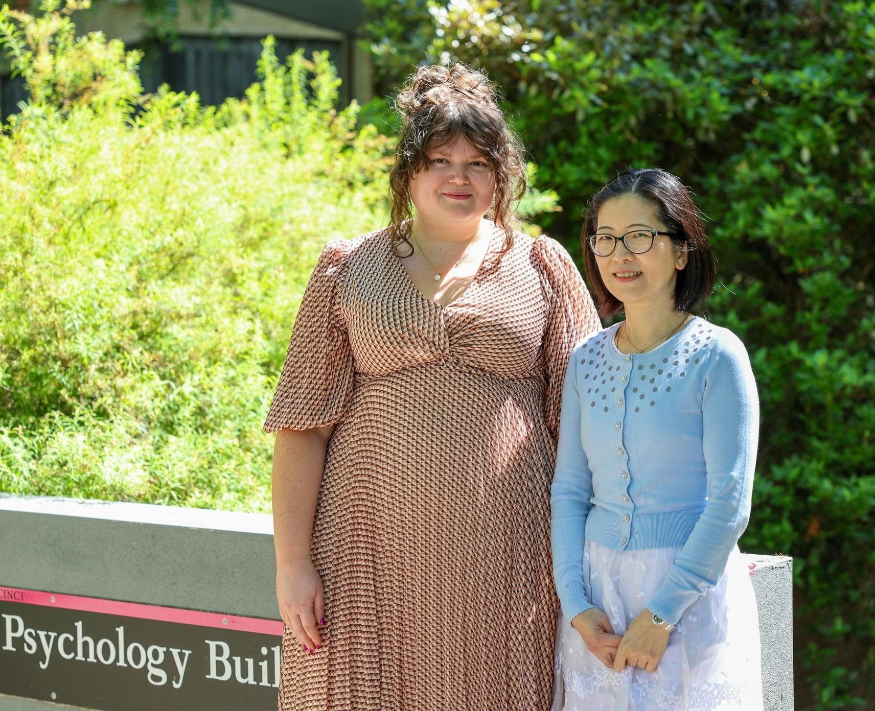 Dr Olivia Evans and Dr Junwen Chen stand in front of the ANU psychology building